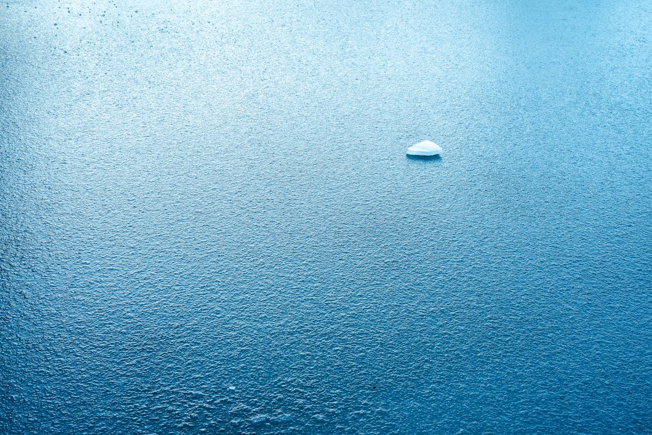A serene scene of a small ice floe floating on textured turquoise water.